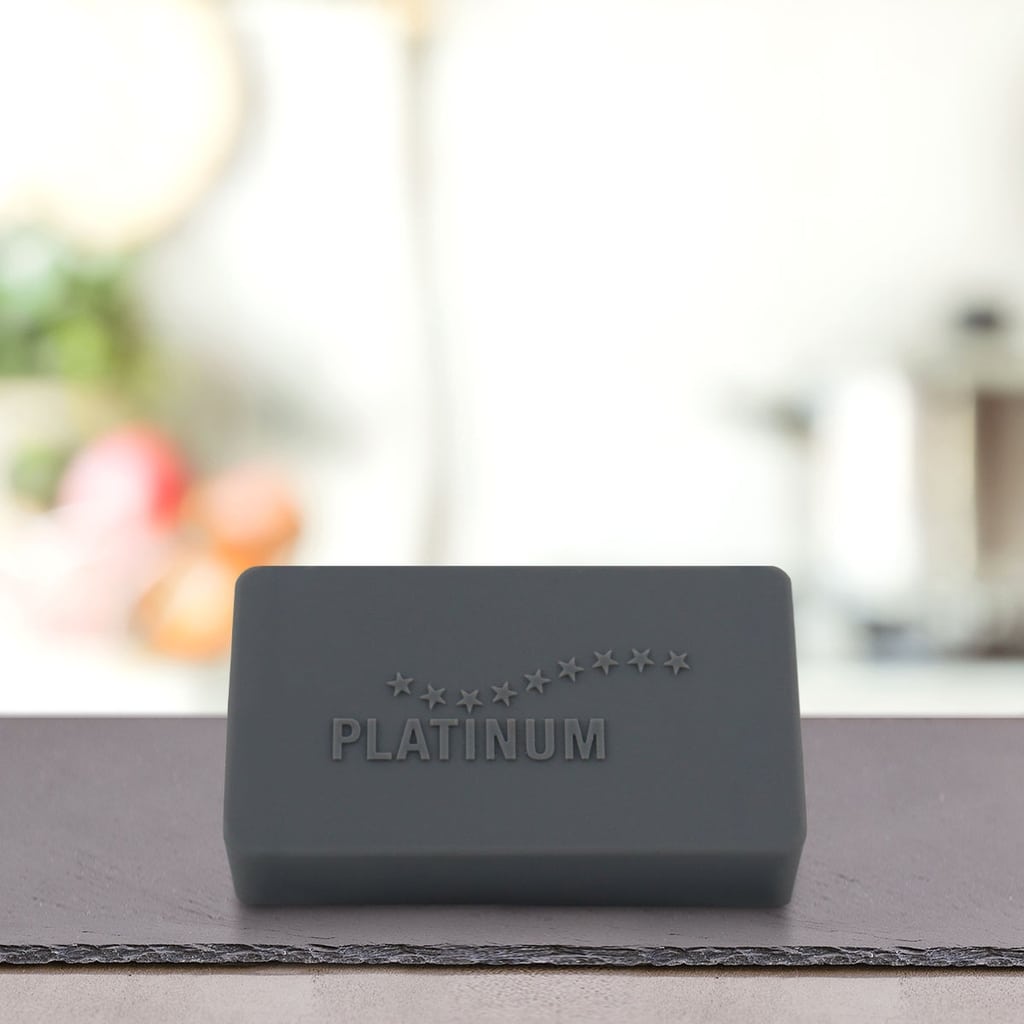 Na pultu stoji črna pravokotna palica z napisom PLATINUM, ki na zamegljenem kuhinjskem ozadju poudarja Štartni paket Puppy - idealno suha in mokra hrana za pse vaše mladiče.